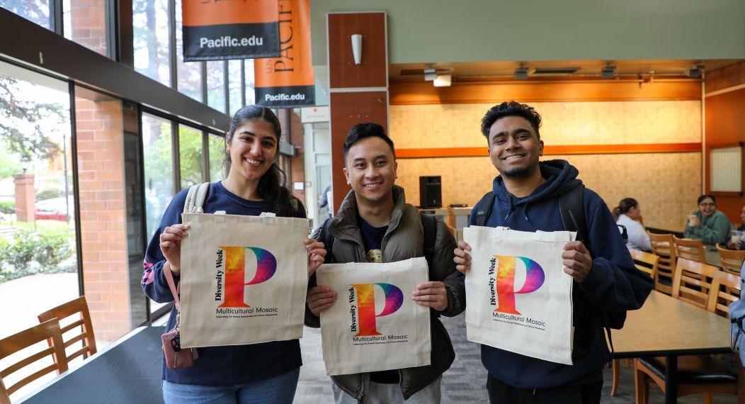 Three students hold tote bags